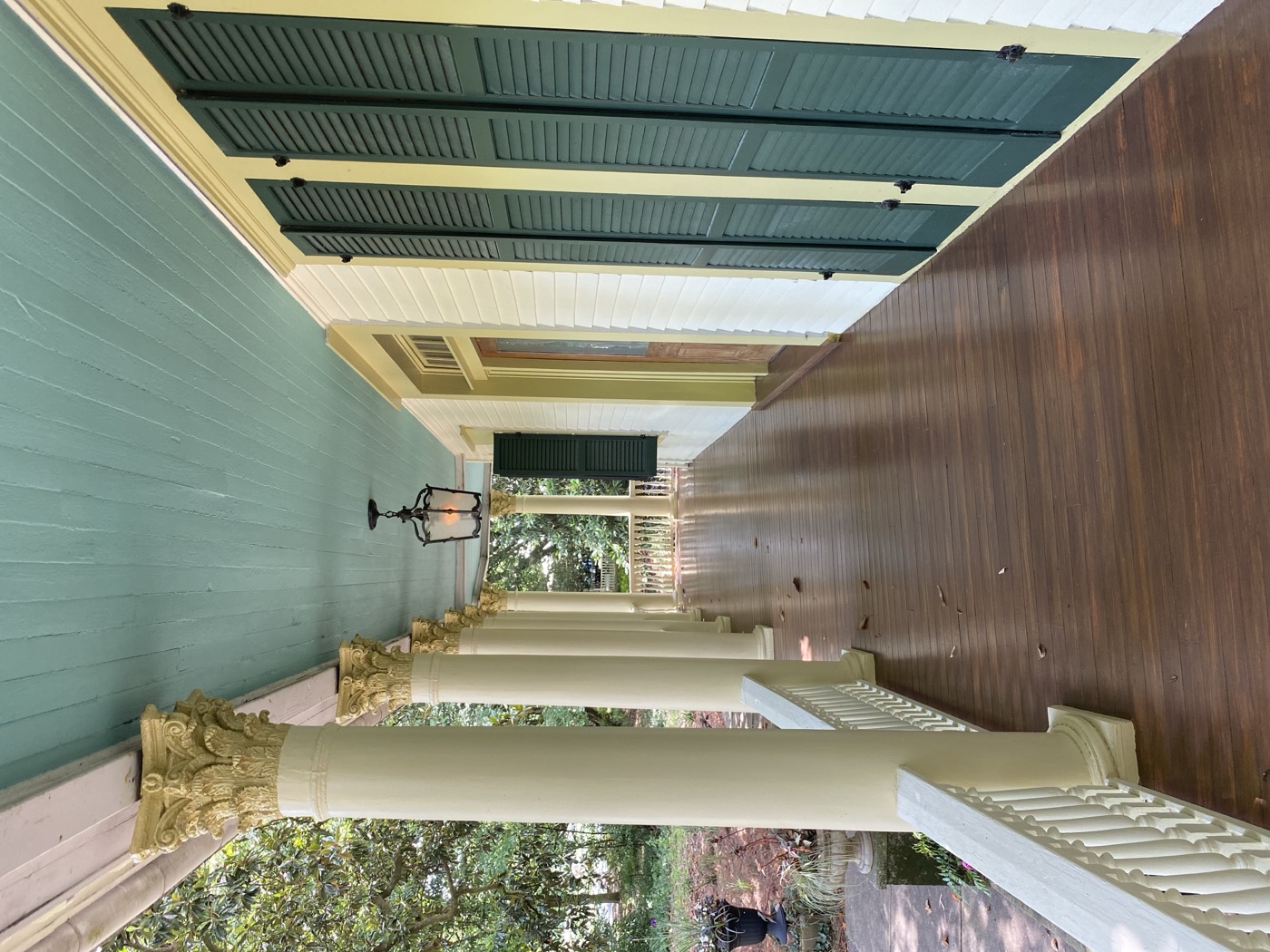 A long front porch with Corinthian columns, a heart-pine floor and tall green shutters